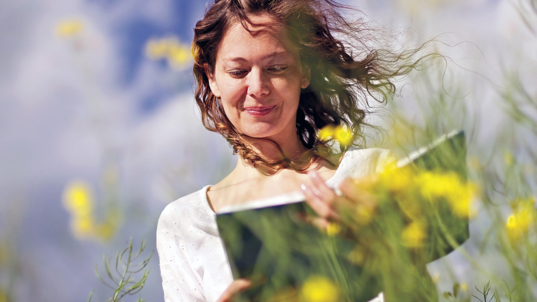 Woman reading in rapeseed field.