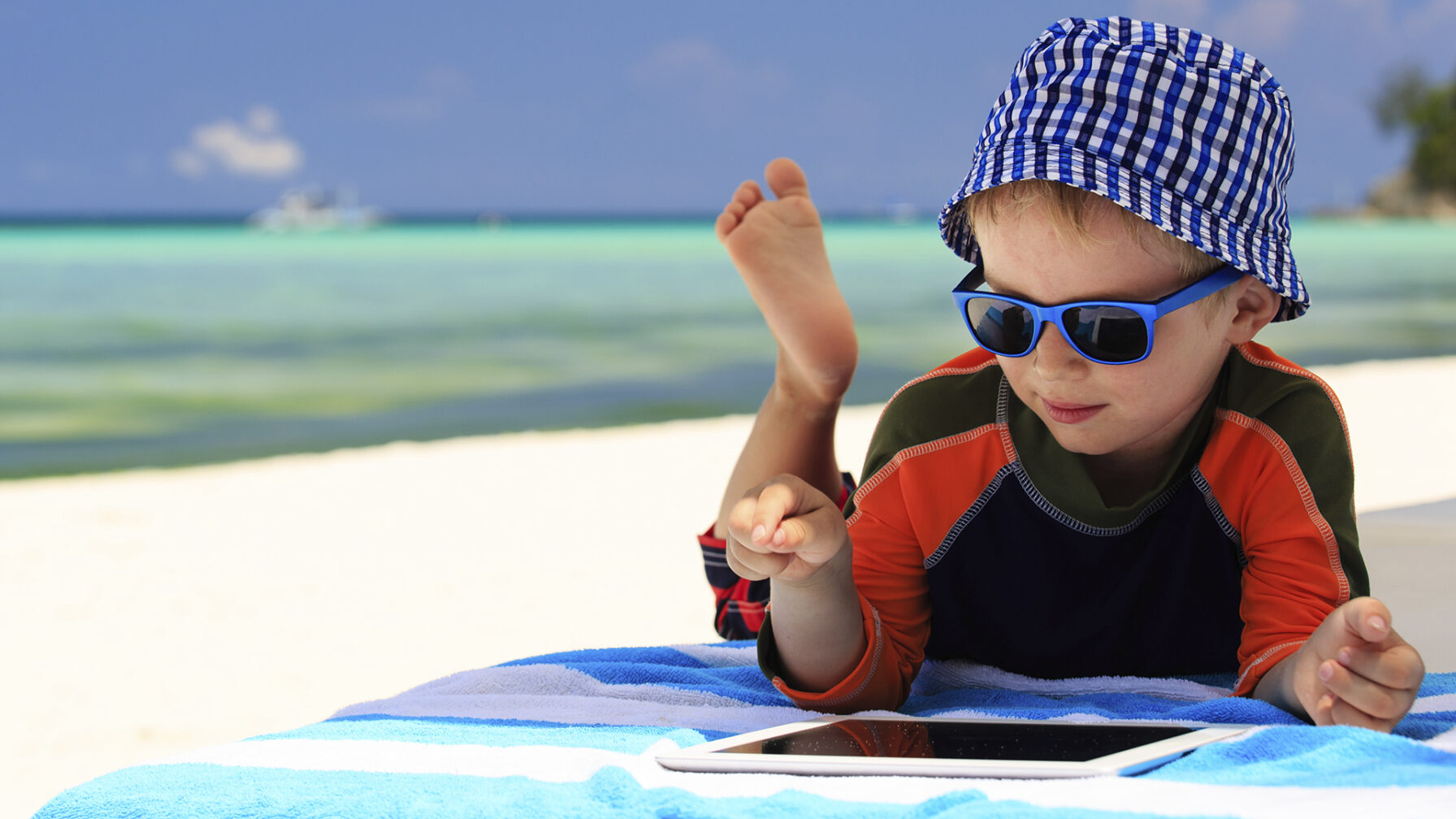 Little boy playing on touch pad at beach