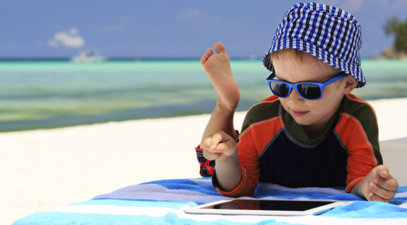 Little boy playing on touch pad at beach