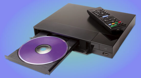 Blue ray player with disk and remote control on white background