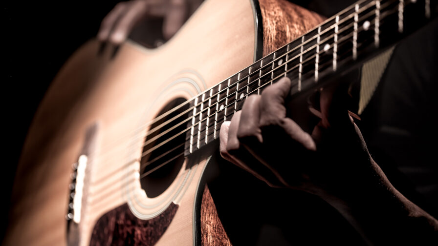 Man playing acoustic guitar on dark background. a musical concept.