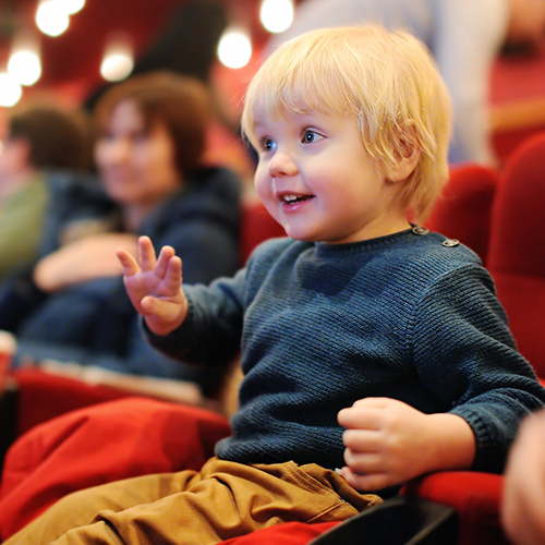 Cute toddler boy watching cartoon movie in the cinema